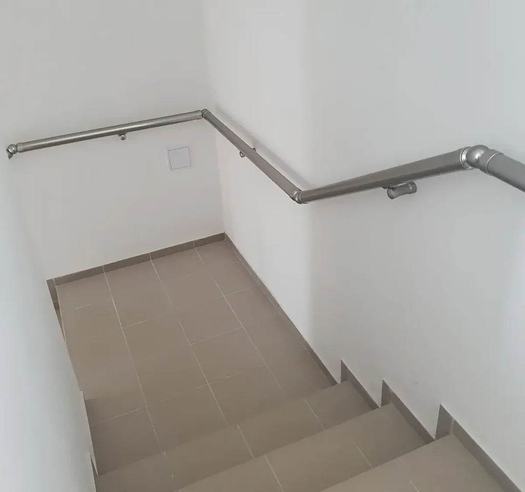 Nerezové madlo na zeď namontované podél vnitřního schodiště v moderním domě.