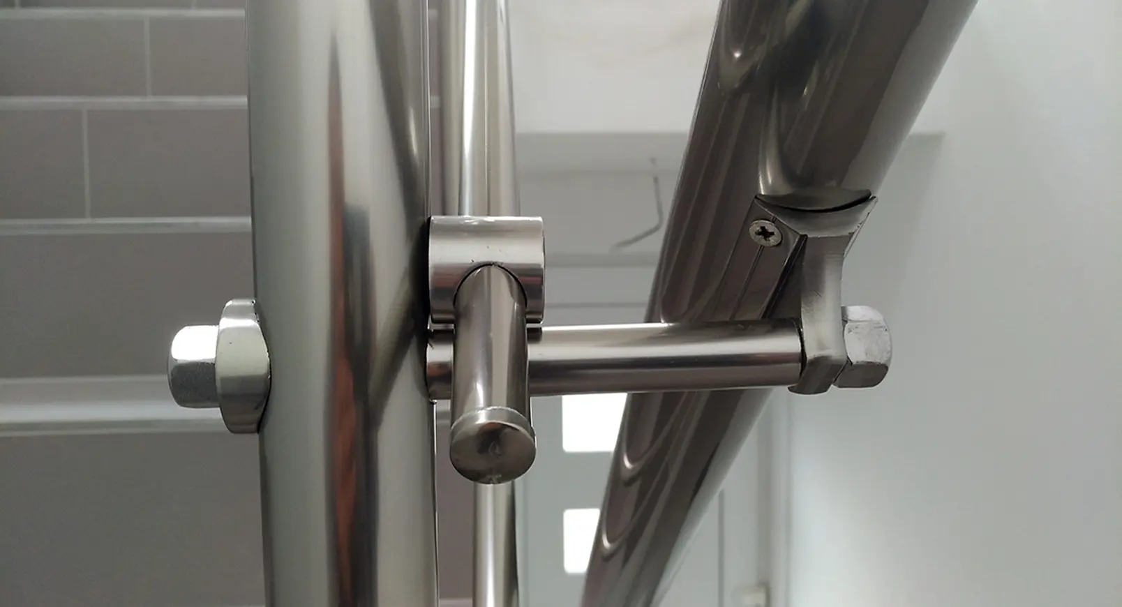 Detail nerezového úchytu pro přídavné madlo na stěnu u vnitřního schodiště.