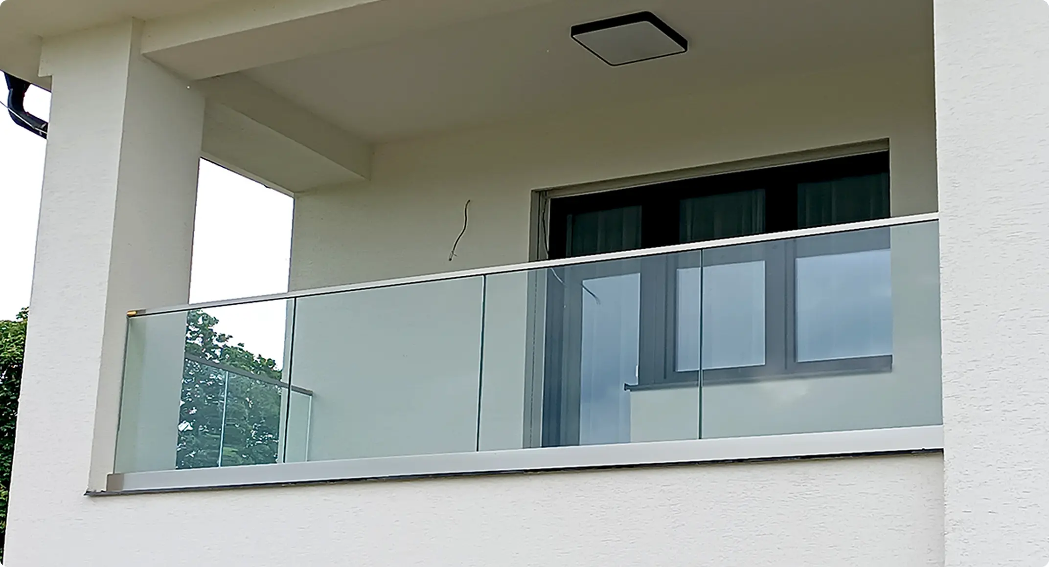 Skleněné zábradlí s hliníkovým profilem na moderní bílé lodžii.