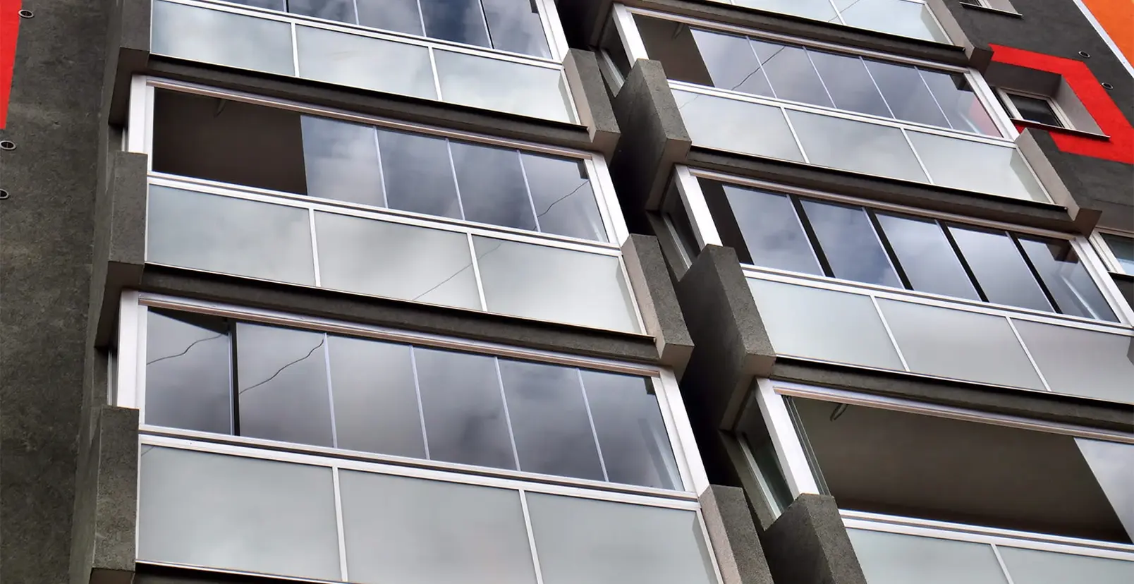 Skleněné zábradlí s hliníkovou konstrukcí na modernizovaném bytovém domě.